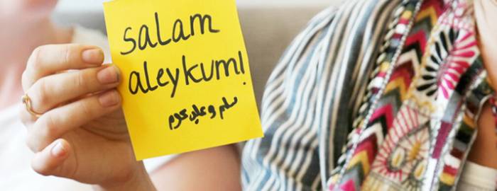 Photo two people, one holding a post-it note that says Salam Aleykum.