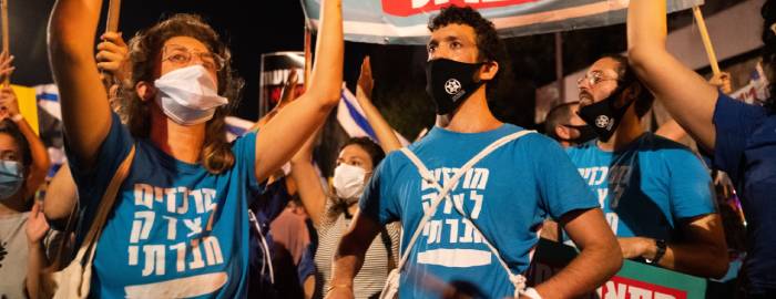 Members of the Tzedek Centers hold signs and march